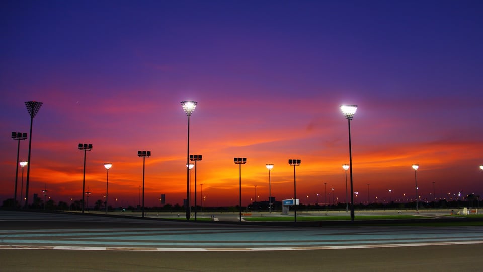 Floodlights along the Yas Marina Circuit track under a dusk sky