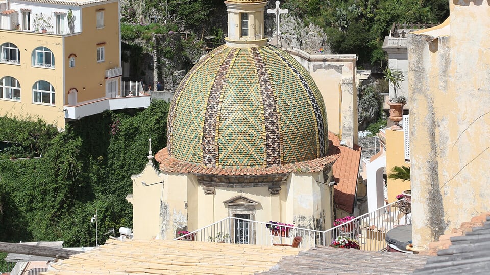 The green and yellow majolica dome of Santa Maria Assunta among the houses of Positano