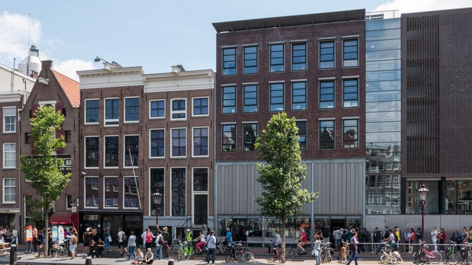 The Anne Frank House museum buildings on the Prinsengracht canal in Amsterdam, with visitors queuing along the quay
