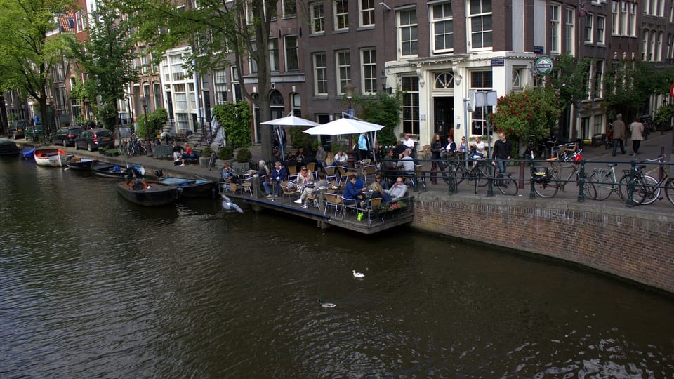 Canal houses and a waterside cafe terrace along the Egelantiersgracht in Amsterdam's Jordaan neighbourhood