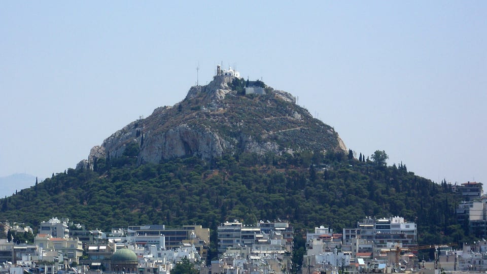 The pine-covered slopes and rocky summit of Lycabettus Hill rising above Athens