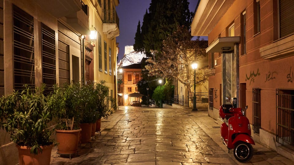 Kidathineon Street in Plaka at dusk, with lamplit paving and a parked scooter