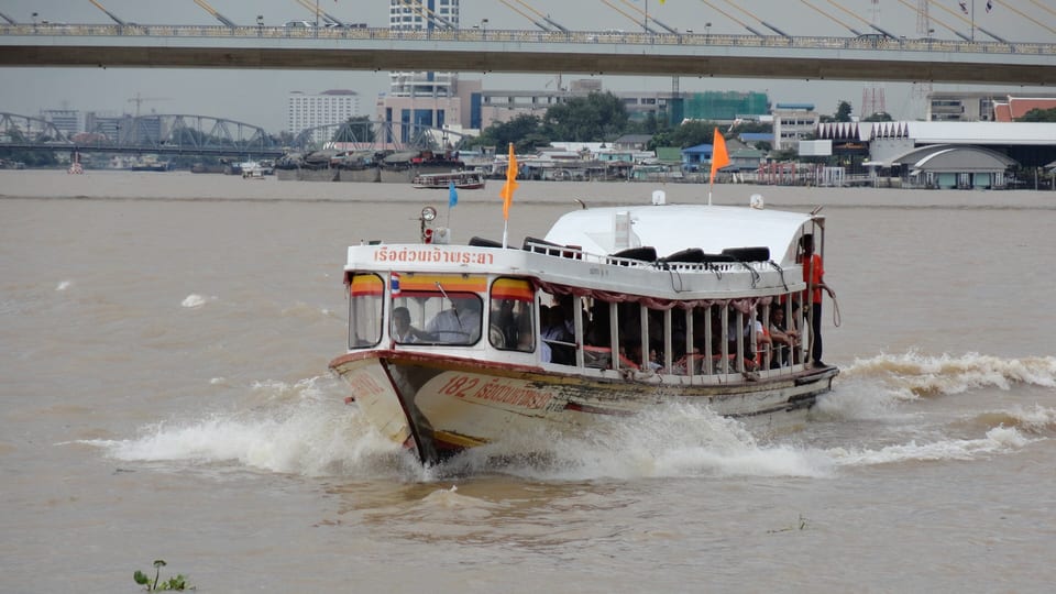 An orange-flag Chao Phraya Express Boat under way on the Chao Phraya River in Bangkok