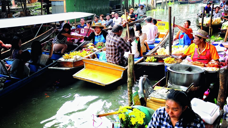 Vendors selling food from boats crowding a canal at Damnoen Saduak Floating Market