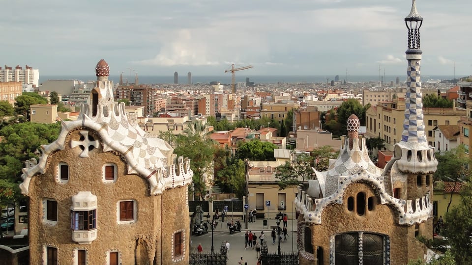 Gaudí's mosaic-roofed gatehouses at the entrance to Park Güell with Barcelona rooftops behind