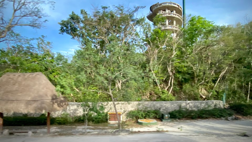 The road-side approach to Xplor adventure park, with its timber entrance canopy and jungle on both sides of the driveway