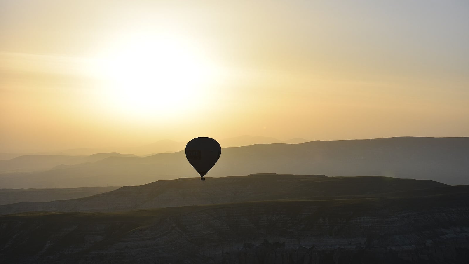 Hot air balloons rising over Cappadocia at sunrise