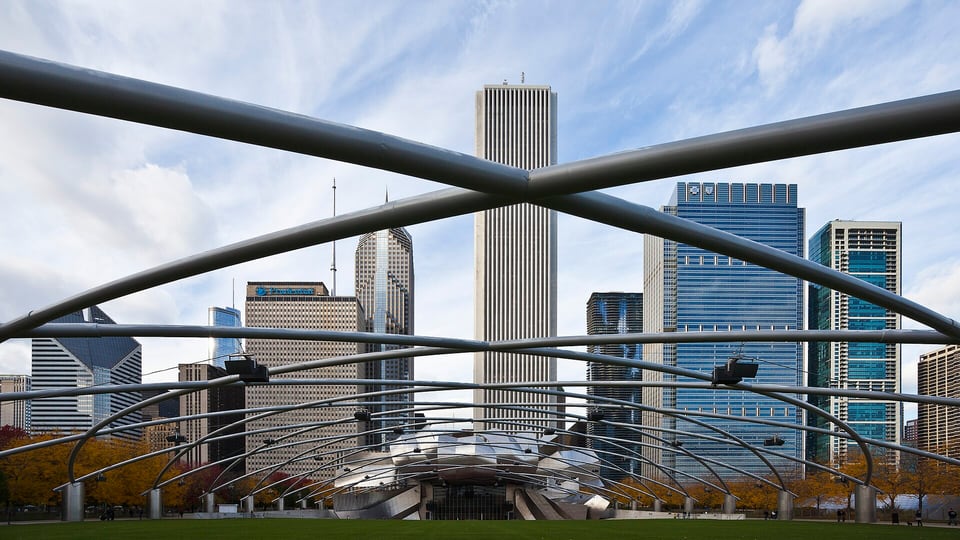 Steel trellis of the Jay Pritzker Pavilion in Millennium Park beneath Loop towers