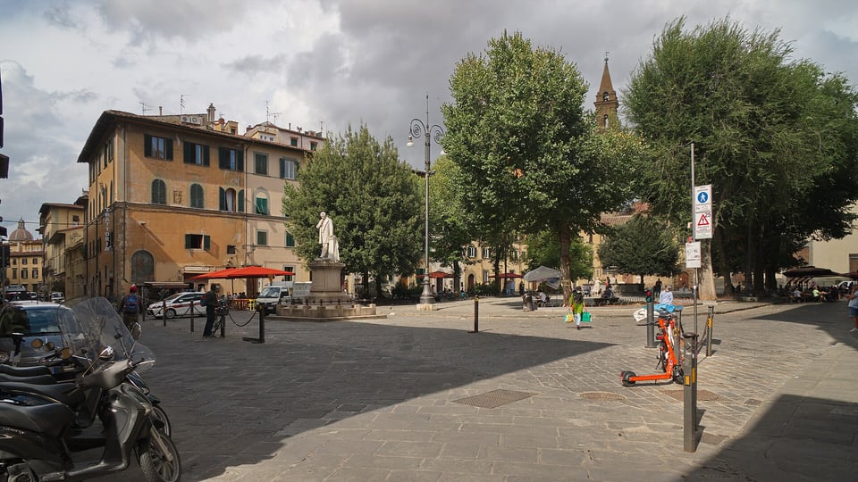Piazza Santo Spirito in the Oltrarno, with a monument, plane trees, café terraces and a church bell tower