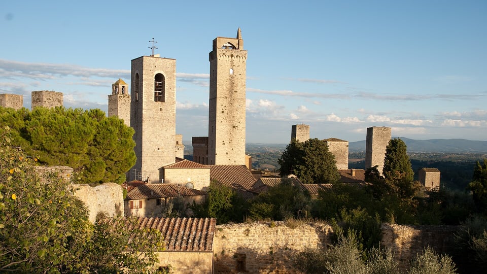 Medieval stone towers of San Gimignano above olive trees and Tuscan hills