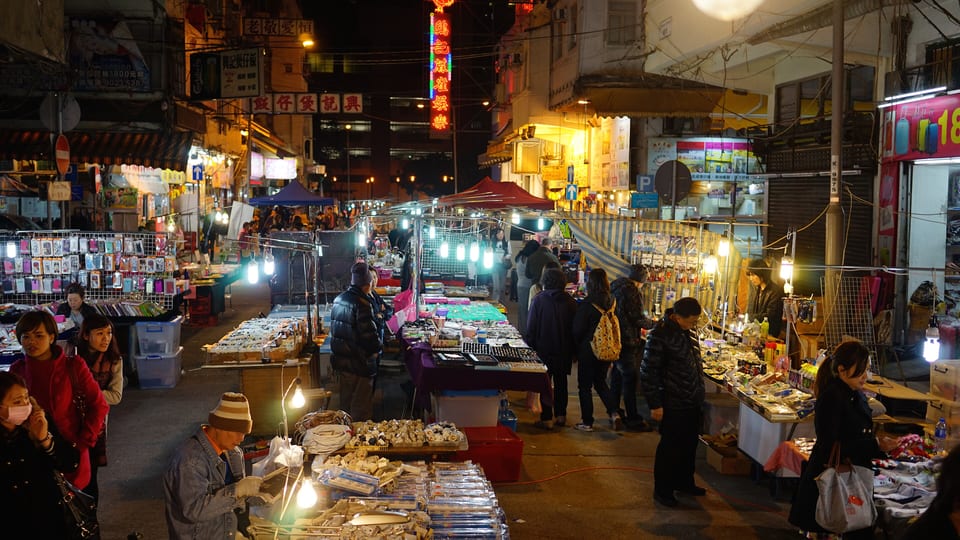Shoppers browsing lit stalls at Temple Street Night Market in Kowloon after dark