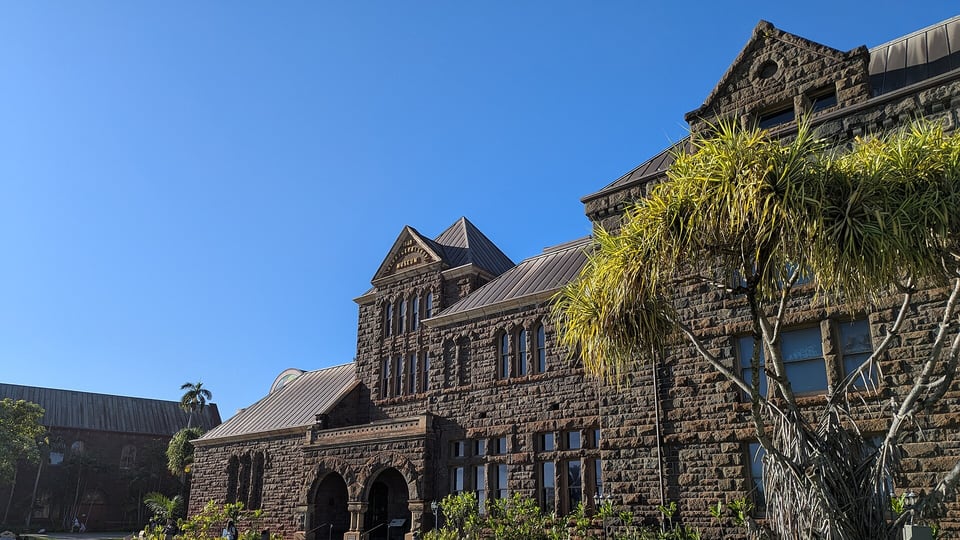 The stone halls of Bishop Museum beside a lawn in Kalihi