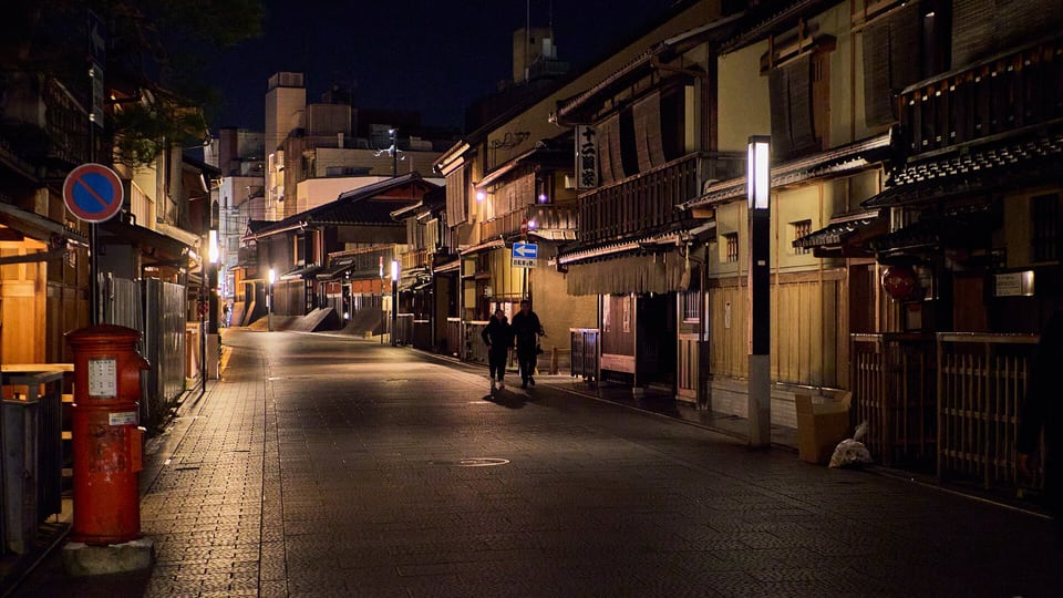 Wooden machiya townhouses along a quiet street in Gion at night