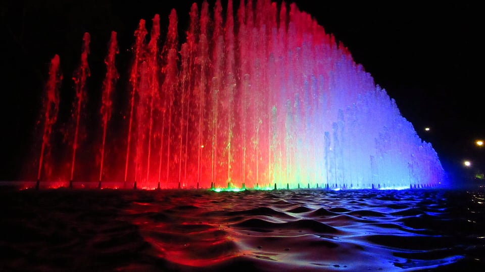 A fountain lit in red and blue at night in the Magic Water Circuit, Parque de la Reserva