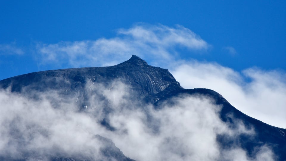 Mount Kinabalu summit rising through clouds in Sabah