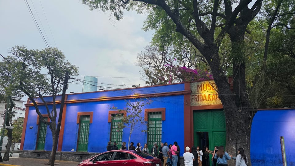 Street front of the Casa Azul in Coyoacán beneath tall trees