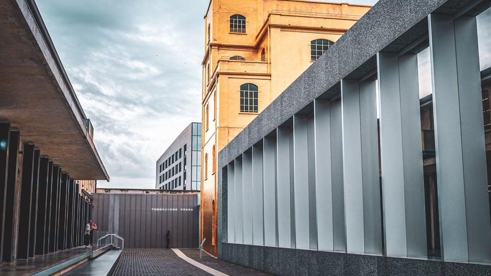 The contemporary architecture of Fondazione Prada in Milan, with a gold-toned building and courtyard walkway