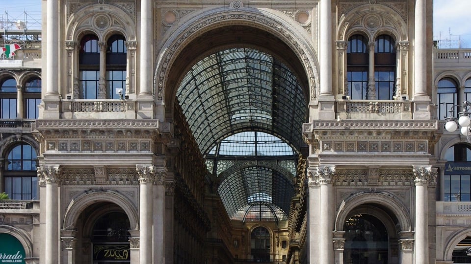 The glass roof and ornate entrance arches of Galleria Vittorio Emanuele II in Milan