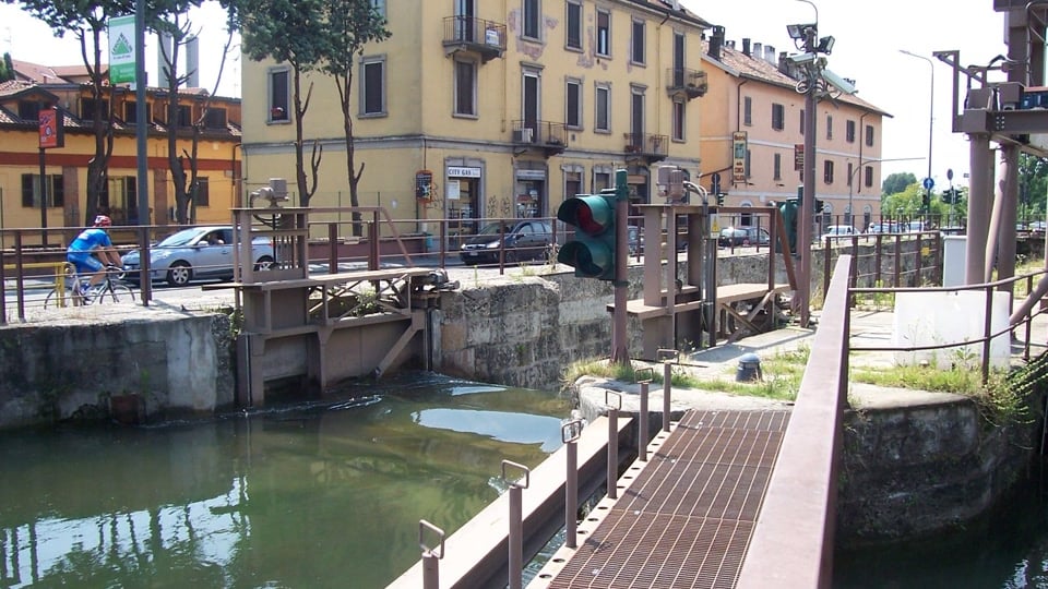 The Naviglio Pavese canal in Milan with waterside buildings, a footbridge and cycling path