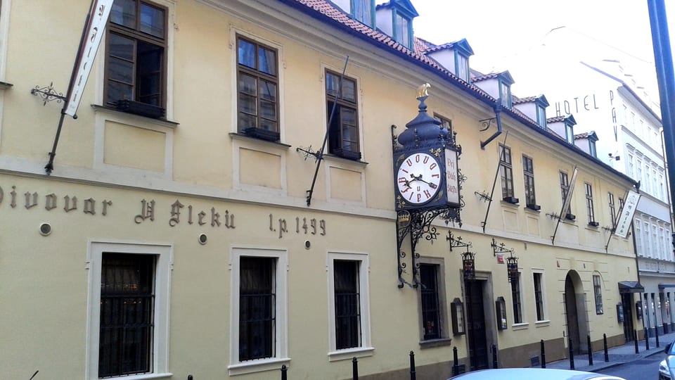 The street facade of the U Fleků brewery and beer hall in Prague's New Town, with its painted sign and hanging clock