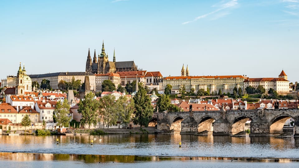Prague Castle and St Vitus Cathedral above the Malá Strana rooftops, with Charles Bridge crossing the Vltava below