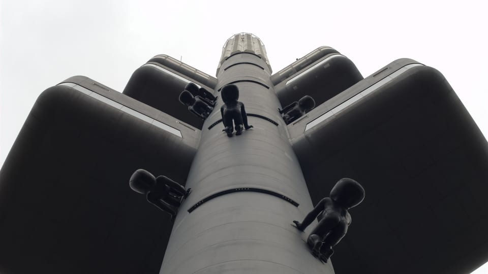 Sculptures of crawling babies climbing the Žižkov Television Tower in Prague, seen from below