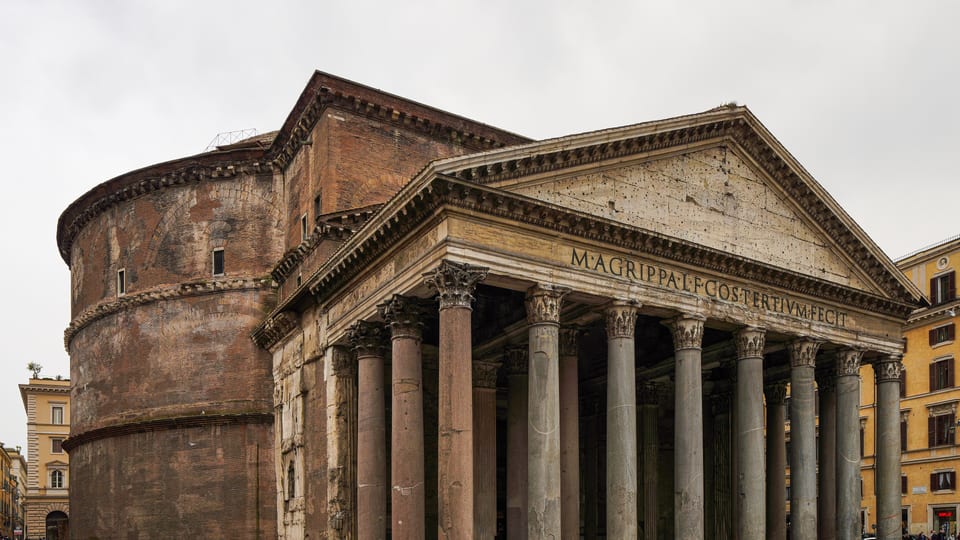 The portico columns and pediment of the Pantheon in Rome, with its brick rotunda to the left