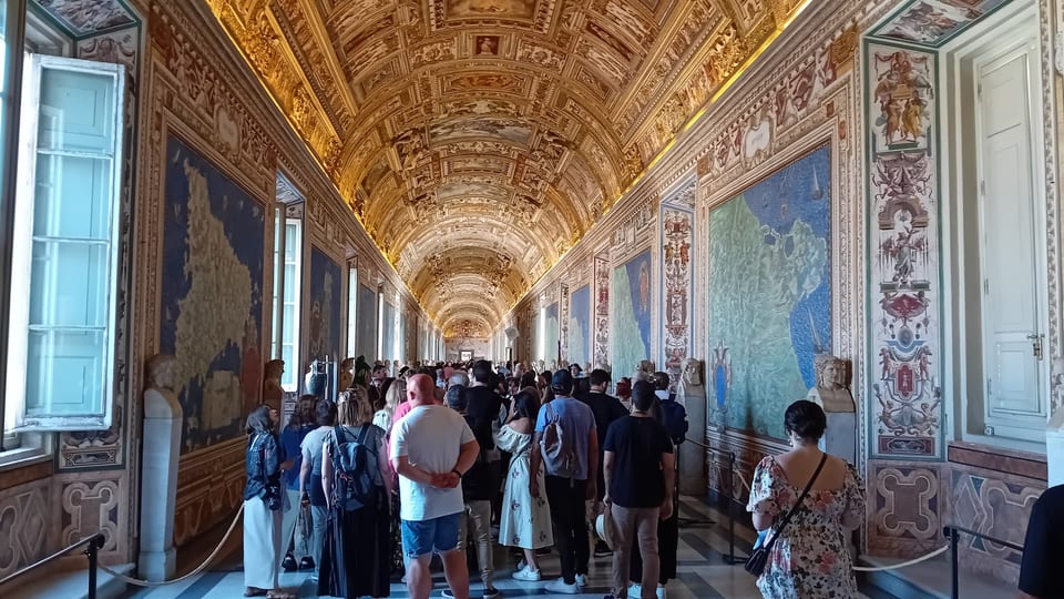 Visitors walking through the Gallery of Maps in the Vatican Museums beneath its gilded, frescoed vault