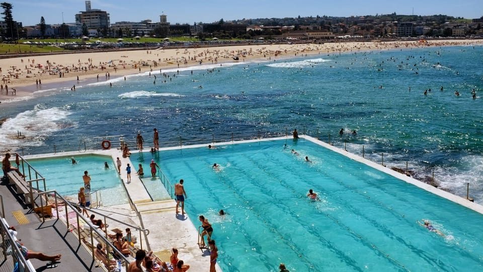 Swimmers in the Bondi Icebergs ocean pool with the curve of Bondi Beach behind