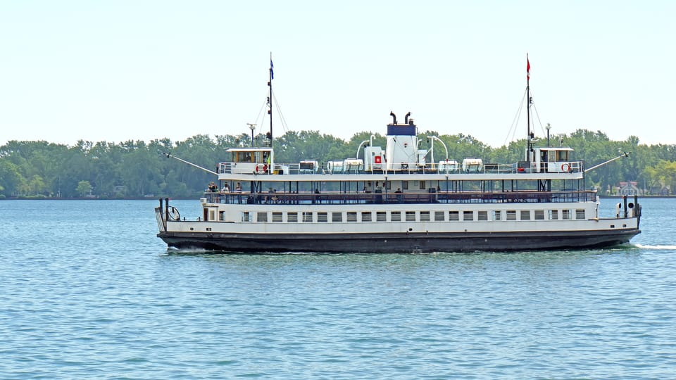 A Toronto Island ferry crossing the harbour with the tree-lined shore of the islands behind