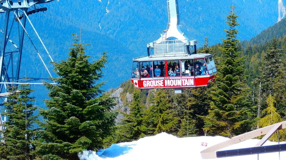 Grouse Mountain Skyride cabin climbing above snow and forested peaks