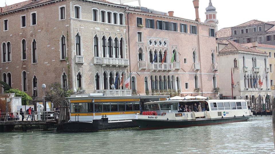 Two vaporettos at a Grand Canal landing stage in front of the waterfront palaces