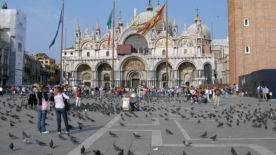 The front of St Mark’s Basilica across the paved square with the campanile at right