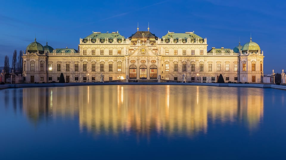 The Upper Belvedere palace in Vienna lit at dusk and reflected in the pool in front of it