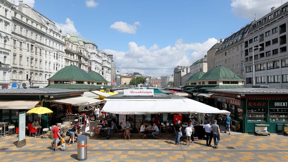 Market stalls and cafe awnings at the Naschmarkt in Vienna, lined by apartment buildings
