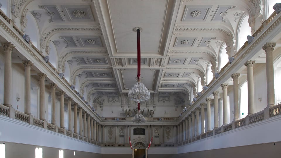 The white arcaded Winter Riding School arena of the Spanish Riding School in Vienna's Hofburg, with its chandelier