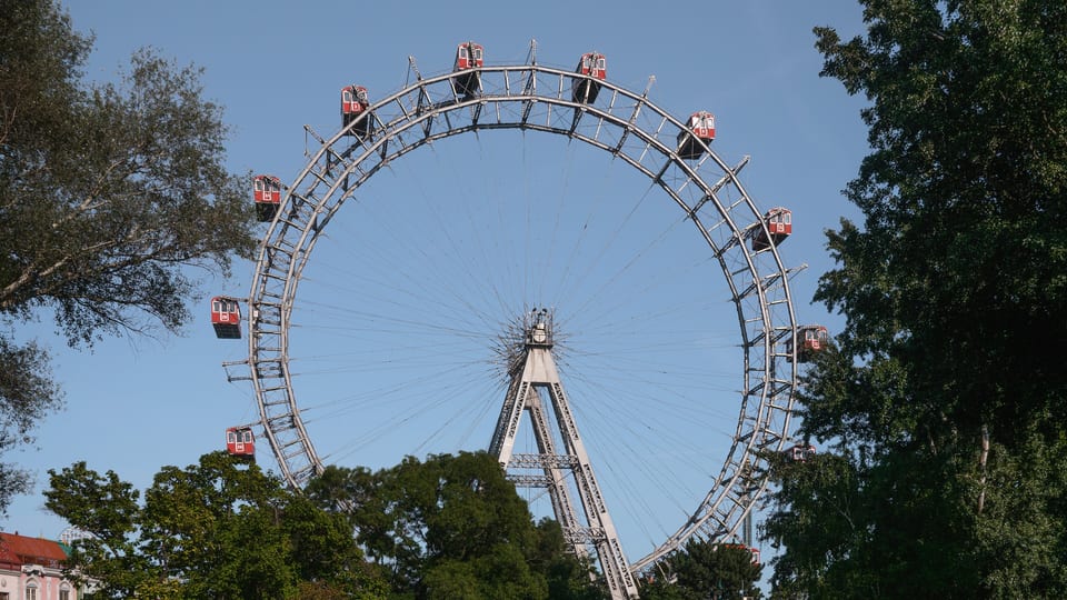 The Wiener Riesenrad giant Ferris wheel in Vienna's Prater with its red gondolas, framed by trees